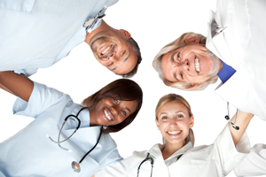 This is a picture of four medical professionals all looking down and smiling at the camera for a picture.